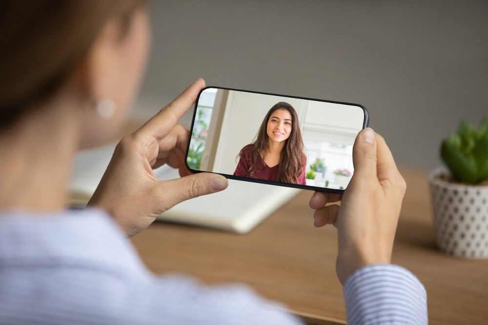 A person talks through a smart camera on his smartphone. A person at work can check what is happening at home on a smart camera.