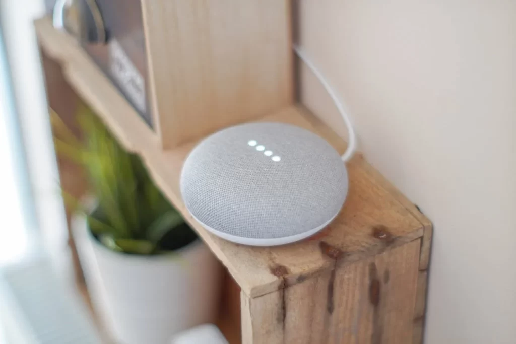 Google Home Kit asystent głosowy w mieszkaniu leży na drewnianej półce.